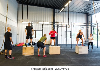 Group of young male and female athletes box jumping