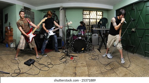 Group Of Young Male Musicians Playing On Messy Garage