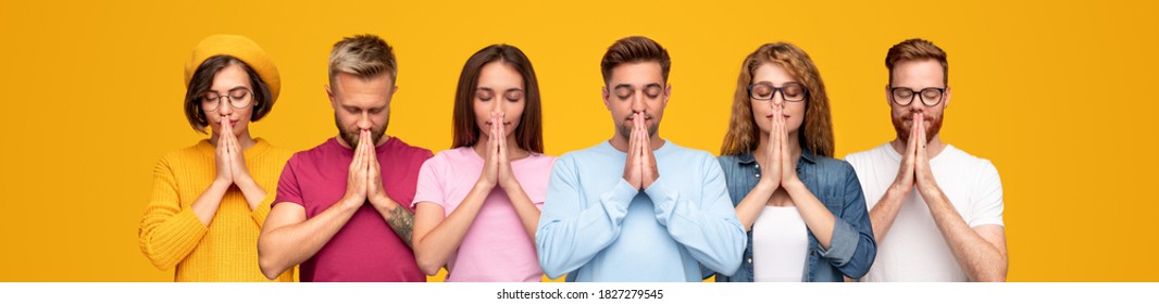 Group Of Young Man And Women Praying With Clasped Hands And Closed Eyes Against Yellow Background