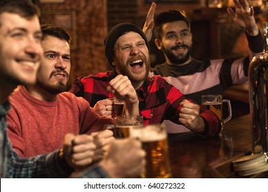 Group Of Young Men Cheering On Their Favorite Football Team Watching The Game On TV At The Local Pub Having Beer Friends Friendship Fans Fun Leisure Activities Drinking Bar Restaurant Emotions Concept