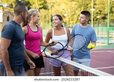 Group of young men and women having conversation about tennis game on outdoor court. - Powered by Shutterstock