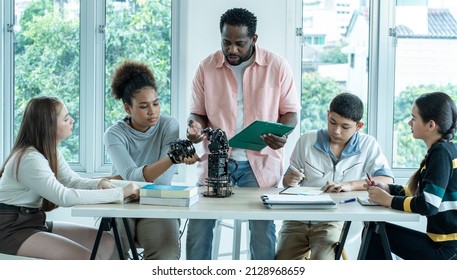 Group of young men and women sit in a class with an African American teacher teaching robotic physics in a high school. Educational concept