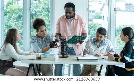 Group of young men and women sit in a class with an African American teacher teaching robotic physics in a high school. Educational concept