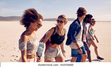 Group of young men and women walking down a beach. Diverse group of friends on beach . - Powered by Shutterstock