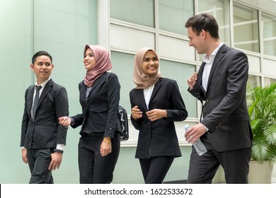 A Group Of Young Mixed Asian Executive At The Corridor Walking And Talking To Each Other