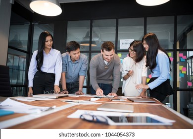 Group of young modern people in casual wear planning business strategy. Business team analyzing income charts and graphs. Setup studio shooting.