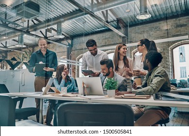Group of young modern people in smart casual wear communicating and using modern technologies while working in the office    - Shutterstock ID 1500505841
