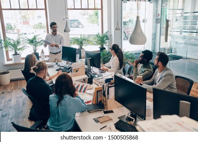 Group of young modern people in smart casual wear communicating and using modern technologies while working in the office - Shutterstock ID 1500505868