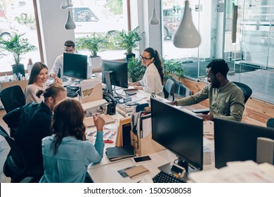 Group of young modern people in smart casual wear communicating and using modern technologies while working in the office        - Shutterstock ID 1500508058
