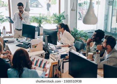 Group of young modern people in smart casual wear communicating and using modern technologies while working in the office - Shutterstock ID 1500510938
