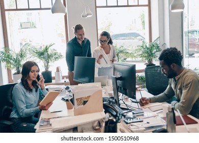 Group of young modern people in smart casual wear communicating and using modern technologies while working in the office         - Shutterstock ID 1500510968
