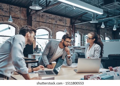 Group of young modern people in smart casual wear communicating and using modern technologies while working in the office - Shutterstock ID 1511800553