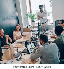 Group of young modern people in smart casual wear communicating and using modern technologies while working in the office - Shutterstock ID 1557492998