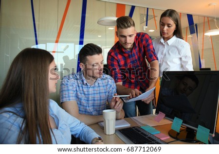 Group of young modern people in smart casual wear having a brainstorm meeting while standing in the creative office.