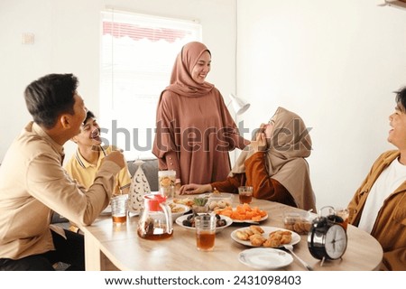 Group of young moslem people talking and laughing while gathering at a dining table