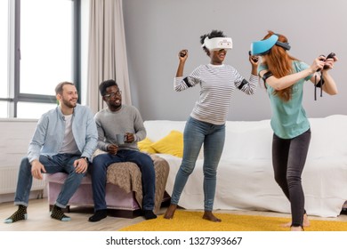 Group Of Young Multicultural Diverse Friends Using Virtual Reality Headsets Having Fun At College Campus. African Girl And Caucasian Red-haired Woman In VR Glasses Making Virtual Tour In Shopping Mall