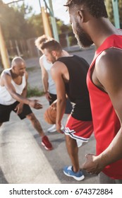 group of young multicultural men playing basketball on court