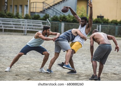 group of young multicultural men playing football on court
