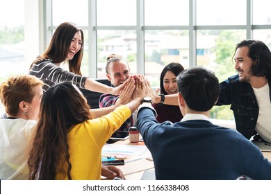 group of young multiethnic diverse people gesture hand high five, laughing and smiling together in brainstorm meeting at office. Casual business with startup teamwork community celebration concept. - Shutterstock ID 1166338408
