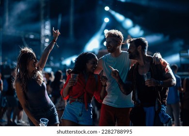 A group of young multiethnic friends are dancing at a music festival at a concert in the open. - Powered by Shutterstock