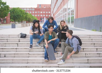 Group of young multiethnic friends sitting on a staircase talking to each other, with skateboard, having fun - friendship, relaxing concept - Powered by Shutterstock