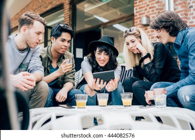Group of young multiethnic friends sitting in a bar having a drink, talking to each other holding a smart phone, having fun - happy hour, friendship, relax concept - Shutterstock ID 444082576