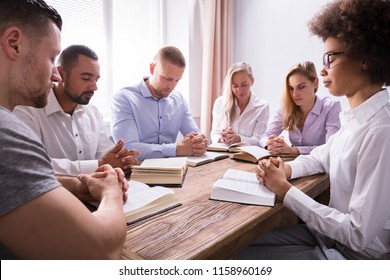 Group Of Young Multiethnic People Reading Bible Over Wooden Desk