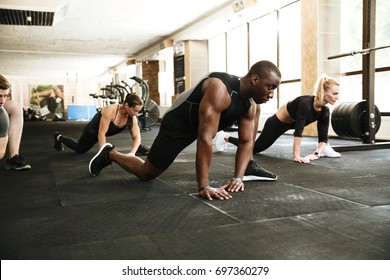 Group Of Young Multiethnic People Stretching Legs At The Gym
