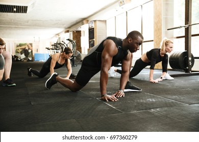 Group of young multiethnic people stretching legs at the gym - Powered by Shutterstock