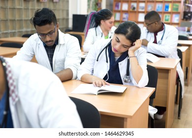 a group of young multiethnic races, medical students. Read textbooks while sitting at a desk. Dullness of exams, study