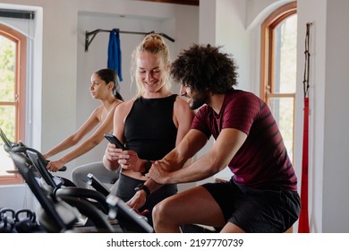 Group Of Young Multiracial Friends On Exercise Bike With Mobile Phone At The Gym