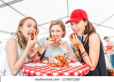 Group Of Young Multiracial Girl Friends Eating Seafood Crab Or Crawfish At A Outdoor Restaurant