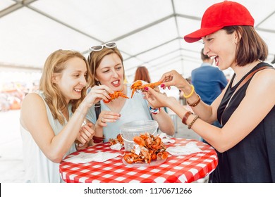 Group Of Young Multiracial Girl Friends Eating Seafood Crab Or Crawfish At A Outdoor Restaurant