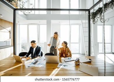 Group Of A Young Office Employees Having Some Office Work At The Large Meeting Table, Wide View On The Spacious Room With Large Windows