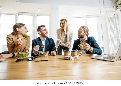 Group Of A Young Office Workers Eating Salads And Drinking Coffee At The Modern Office Canteen. Concept Of A Healthy Takeaway Food On The Work