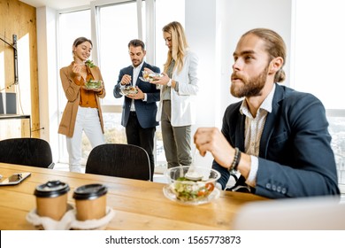 Group Of A Young Office Workers Eating Salads And Drinking Coffee At The Modern Office Canteen. Concept Of A Healthy Takeaway Food On The Work