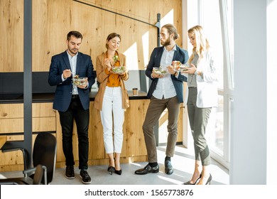 Group Of A Young Office Workers Eating Salads And Drinking Coffee At The Modern Office Canteen. Concept Of A Healthy Takeaway Food On The Work