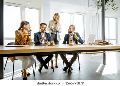 Group Of A Young Office Workers Eating Salads And Drinking Coffee At The Modern Office Canteen. Concept Of A Healthy Takeaway Food On The Work