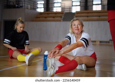 Group of young and old women, sports team players. in gym stretching, warming up before match. - Powered by Shutterstock