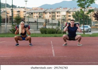 A Group Of Young People In Aerobics Class Performing Bag Squat Exercise Outdoor - Powered by Shutterstock