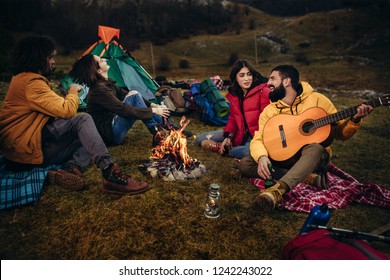 Group of young people around camp fire.