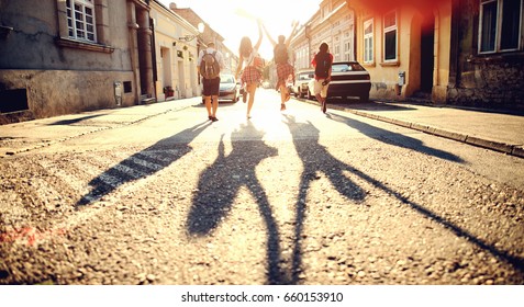 Group of young people with backpacks running through the street. Tourists concept. Exploring the city. - Powered by Shutterstock