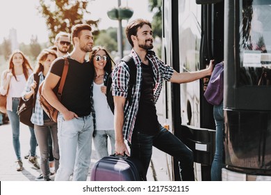 Group of Young People Boarding on Travel Bus. Happy Travelers Standing in Queue Holding Luggage Waiting their turn to Enter Bus. Traveling, Tourism and People Concept. Summer Vacation