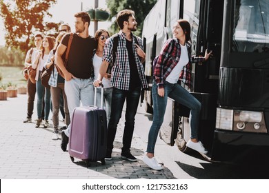 Group of Young People Boarding on Travel Bus. Happy Travelers Standing in Queue Holding Luggage Waiting their turn to Enter Bus. Traveling, Tourism and People Concept. Summer Vacation