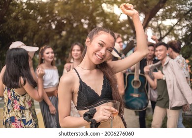 A group of young people in bohemian outfits party away at a music festival or other hippie celebration. A young asian girl dances to the groove. Copyspace on upper left.