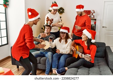 Group Of Young People Celebrating Christmas Singing Carol Song At Home.