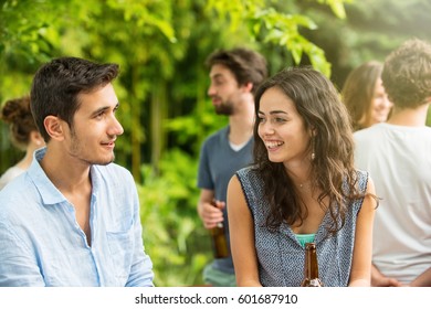 Group of young people celebrating outside. Focus on a beautiful young couple discussing with a beer at hand. Shot with flare - Shutterstock ID 601687910