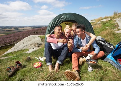 Group Of Young People Checking Mobile Phone On Camping Trip