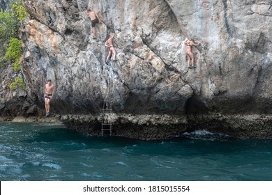 Group Of Young People Climb The Rock Above The Sea. Rock Climbing (deep Water Solo) In Thailand.