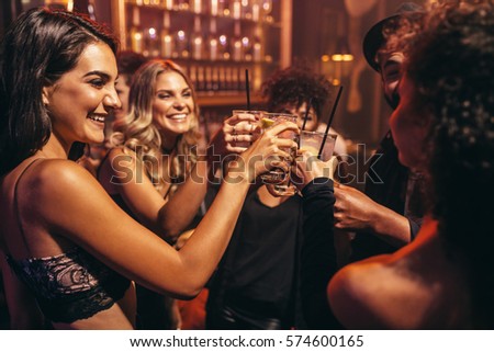 Group of young people with cocktails at nightclub. Best friends partying in a pub and toasting drinks.